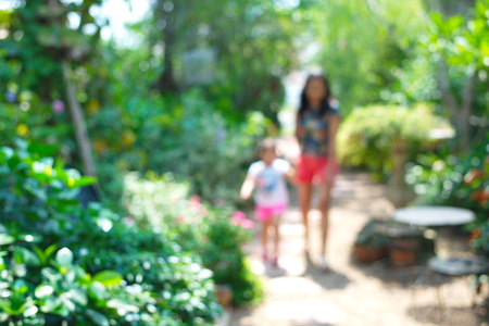 blur woman and kid walking in green garden backgroundの写真素材