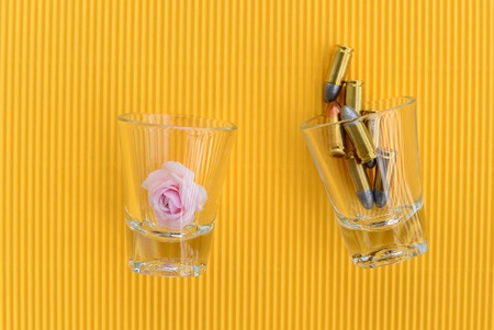 pink rose and bullets in glass on yellow backgroundの写真素材