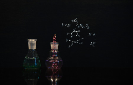 flower in green and violet solution in beaker and flak lab on black chemical backgroundの写真素材