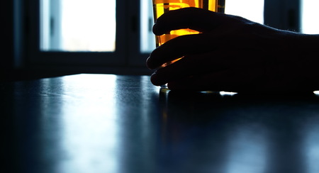 beer glass holding in man hand in dark night on the tableの写真素材