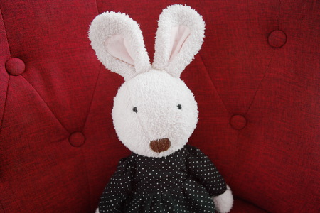 old fluffy rabbit doll sitting on red sofa decoration