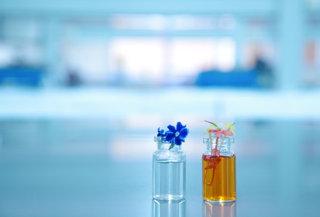 orange violet flower and two vial with science laboratory backgroundの写真素材