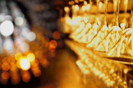 blur haning alcohol drinking glass with bokeh light golden backgroundの写真素材