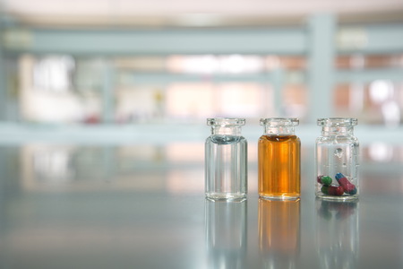 three vials with capsule pill orange and water solution in science laboratory backgroundの写真素材
