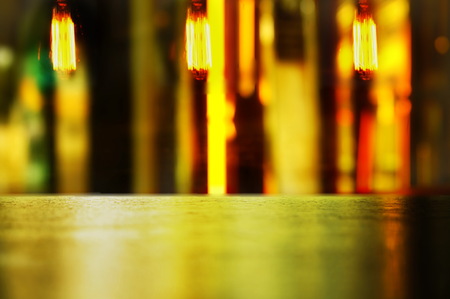 wood table display with vibrant abstract light and bulb lamp in bar in the dark night background