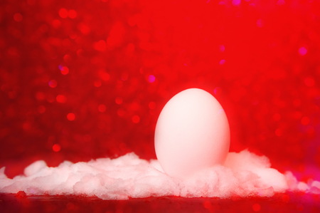 Easter egg in snow with red light bokeh backgroundの写真素材