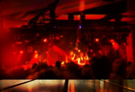 top of wood table with blur red light music performance party in bar pub or club at night backgroundの写真素材