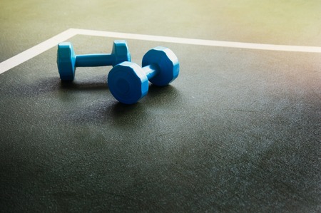 blue dumbbells for health fitness on floor dark green gymnasium sport backgroundの写真素材
