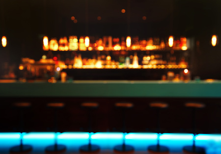 blur alcohol bottle on bar counter party with blue light stool in dark night background