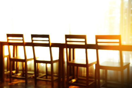 blur four wooden chairs in row with white curtain with orange sunlight backgroundの写真素材