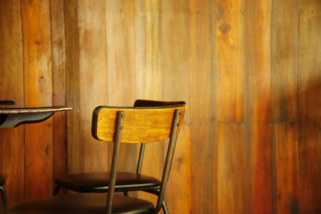 part of vintage style brown wooden chair with wood wall interior of cafe and restaurant background