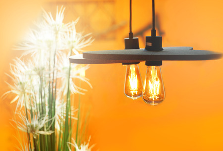 warm tungsten lamp metal with white glass flower on orange interior background