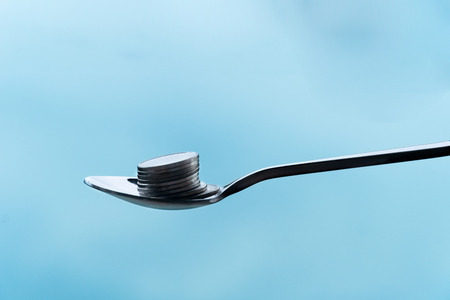 single metal teaspoon with silver coin money pile for food capitalism investment business concept financial backgroundの写真素材