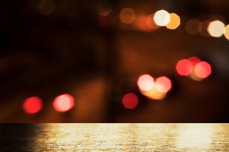 top of golden light on wood table with blur city red orange bokeh street light in the dark night...