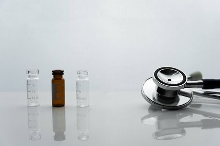 metal stethoscope for doctor health diagnosis with brown and clear glass medical drug therapy in clinic or hospital white backgroundの写真素材
