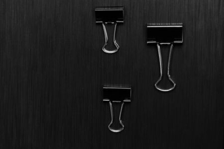three metal black clip for business document office work on dark modern elegant classy backgroundの写真素材