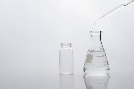 science flask with water drop and vial in clean white research and education chemistry laboratory...