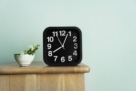 drink tea cup ceramic with wild white green flower and black clock time in morning on wood table and blue interior backgroundの写真素材