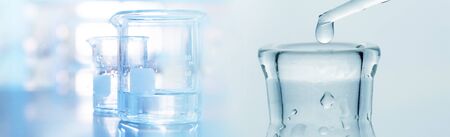 water drop into research glass flask and beaker in soft blue light medical science laboratory banner backgroundの写真素材