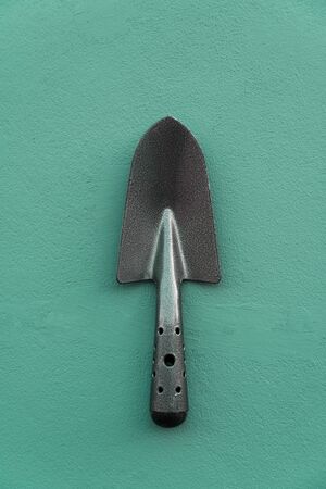 black grey metal trowel on cement dark green wall background tool for gardening or agriculture activity の写真素材