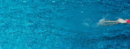 girl legs swimming in the fresh blue pool summer water for vacation web banner background