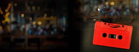 retro red cassette music tape on black light bokeh dark night bar and pub party web banner backgroundの写真素材