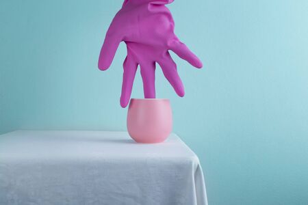 hot tea pastel pink ceramic cup with weird hand in colorful rubber glove cozy blue wall interior fantasy backgroundの写真素材