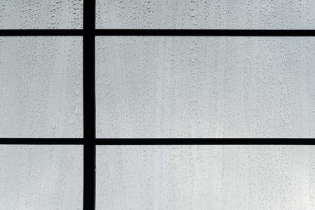 small water drop on glass window black metal frame rainy season grey background
