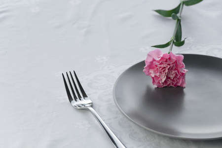 dark grey plate with natural pink carnation flower for food restaurant service backgroundの写真素材