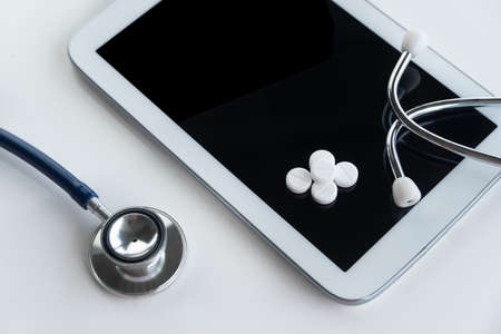 blue stethoscope and pill drug with white tablet for doctor health diagnosis in telemedicine business concept on white backgroundの写真素材