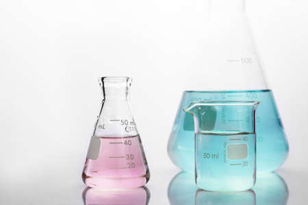pink and blue solution in beaker and flask in white chemistry science laboratory background
