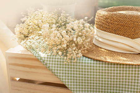 beige woman hat with nature white flower and green fabric picnic mat for summer outdoor activity
