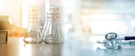 glass flask with text book and doctor stethoscope in medical health science lab banner backgroundの写真素材