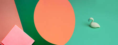 pink red note book and green plastic model of bird on orange colorful paper modern design banner backgroundの写真素材