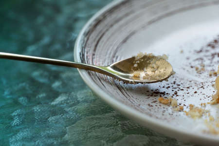 golden metal spoon with white dessert dish on green table food and restaurant backgroundの写真素材