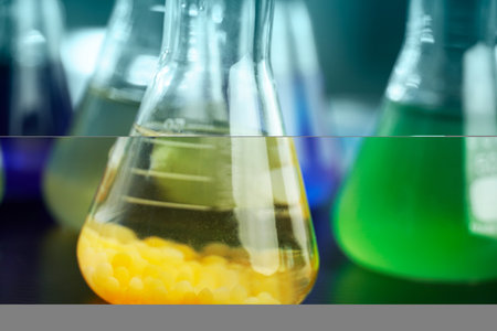 orange and green solution in science glass flask at chemistry research lab backgroundの写真素材