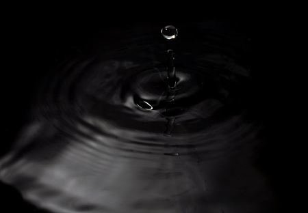 A water drop fall in water, on black backgroundの写真素材