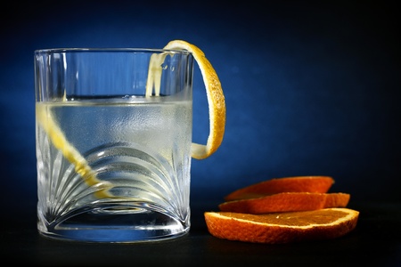 Cold vodka in a glass, with decor oranges and lemon, in black blue  background, part of art beverage backgroundの写真素材