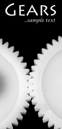 Two white connected cogwheels on black backgroundの写真素材