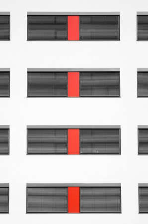 A Building Pattern of some windows divided by a red peace of wallの写真素材