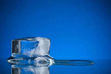 An ice cube on a reflective surfaceの写真素材