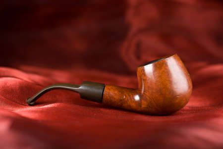 An old smoking pipe isolated over a red fabricの写真素材