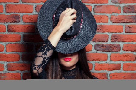 Portrait of a young beautiful girl in black body dresses on the background of a brick wallの写真素材