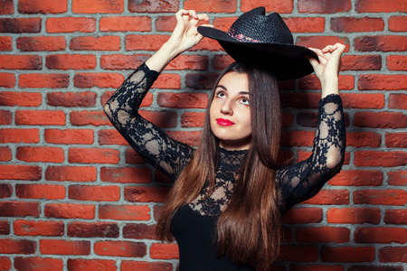 Portrait of a young beautiful girl in black body dresses on the background of a brick wallの写真素材