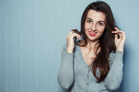 Portrait of a young beautiful girl with the brightly painted lips on a gray background.の写真素材