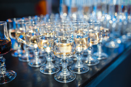 Crystal glasses filled with champagne. The front background is in focus. There are many glasses