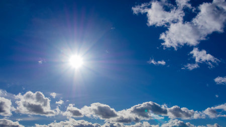 blue sky with sun and cumulus cloudsの写真素材