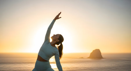 Young woman practicing yoga on the beach at sunrise. Healthy lifestyle concept.の写真素材