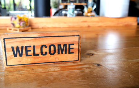 Welcome word on the wood board in the coffee shop or restaurant. The board lay on the table to show...