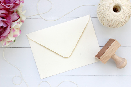 Mockup of envelope with a rubber stamp next to it. Modern trend template for advertising. Flowers and wooden background.の写真素材